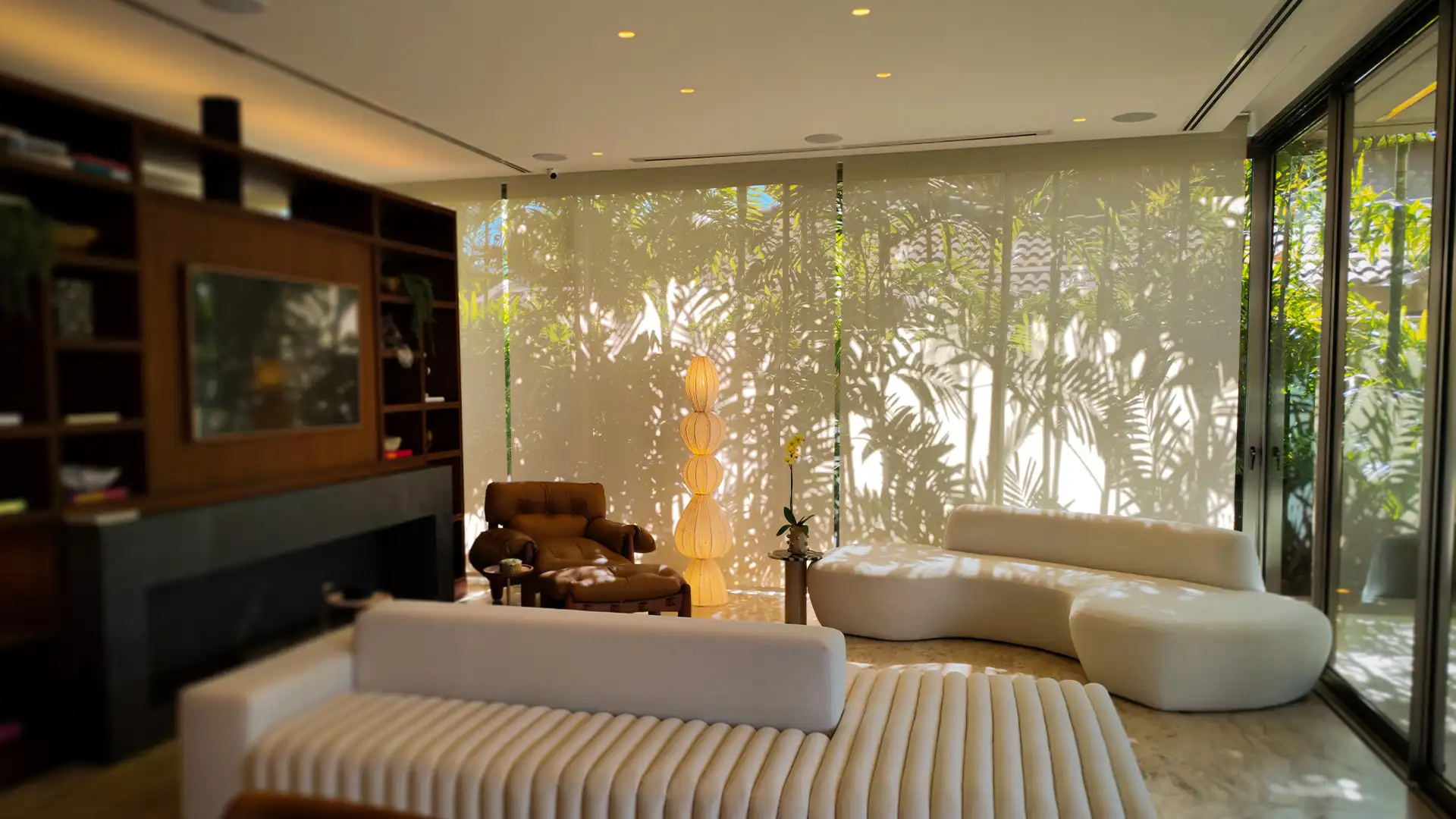 Sombras de palmeiras sendo refletidas em tecido de persiana Rolô Sanlui com acionamento automático